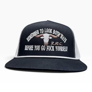 May include: A black trucker hat with a white mesh back and a white cord across the brim. The front features an embroidered white longhorn steer head with brown horns, surrounded by the text "REMEMBER TO LOOK BOTH WAYS" and "BEFORE YOU GO FUCK YOURSELF" in white, along with the letters "R.W.C.".