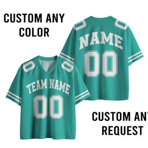 May include: Two teal football jerseys with white accents. One jersey displays "TEAM NAME" and "00", the other displays "NAME" and "00". The text "CUSTOM ANY COLOR" and "CUSTOM ANY REQUEST" are also visible.