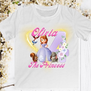 May include: White t-shirt featuring a princess graphic with the name "Olivia" in pink, the number "4", and the words "The Princess". The design includes a princess, squirrel, bunny, birds, and flowers.