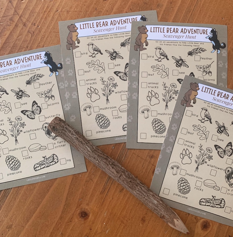 May include: Four beige Little Bear Adventure scavenger hunt cards with illustrations of birds, bees, and other items. A wooden pencil lies across the cards. The text on the cards reads "Little Bear Adventure Scavenger Hunt".