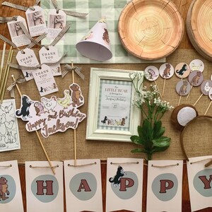 May include: A collection of party supplies with a Little Bear theme. Includes a book, banner, cupcake toppers, plates, a frame, and a headband. The banner spells out "HAPPY" and a sign says "Happy 2nd Birthday Jackson!"