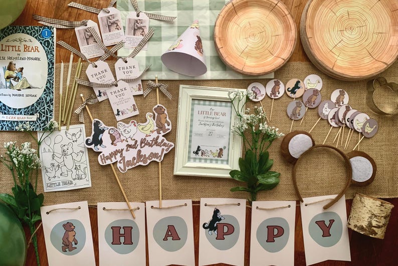 May include: A collection of party supplies with a Little Bear theme. Includes a book, banner, cupcake toppers, plates, a frame, and a headband. The banner spells out "HAPPY" and a sign says "Happy 2nd Birthday Jackson!"