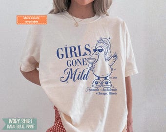 Könnte beinhalten: Ein elfenbeinfarbenes Kurzarm-T-Shirt mit dunkelblauem Grafikdruck. Das Motiv zeigt eine Ente mit Sonnenbrille, Krone und Hausschuhen, die ein Getränk hält. Text: GIRLS GONE Mild, EST. 2020, Amanda's bachelorette, Chicago, Illinois.