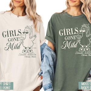 May include: Two t-shirts, one cream and one khaki green, display the text "GIRLS GONE Mild" with a cartoon duck in sunglasses and a cocktail. The shirts also include "Amanda's bachelorette + Chicago, Illinois" and "EST. 2028".