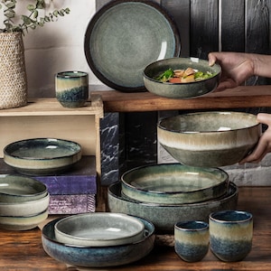 May include: A set of green and blue ceramic bowls and cups. The bowls are of various sizes and shapes, and the cups are all the same size. The bowls and cups have a rustic, handmade look.
