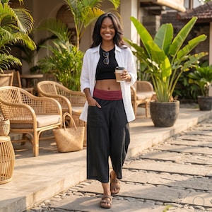 May include: A black cropped tank top, a white button-down shirt, and black wide-leg trousers with a maroon fold-over waistband. The trousers feature side pockets and a subtle vertical striped texture. The outfit is paired with brown sandals.
