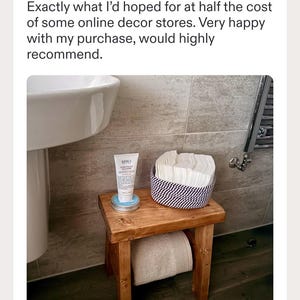 May include: A small wooden stool with four legs and a rectangular top. On the stool sits a white tube of Kiehl's Ultra Facial Cleanser on a round tin, and a round woven basket containing a stack of white square cloths. A beige towel is stored underneath.