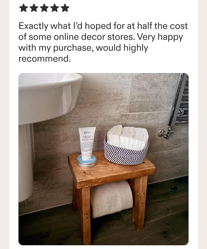 May include: A small wooden stool with four legs and a rectangular top. On the stool sits a white tube of Kiehl's Ultra Facial Cleanser on a round tin, and a round woven basket containing a stack of white square cloths. A beige towel is stored underneath.