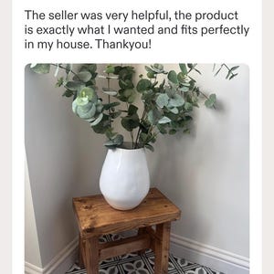 May include: A white ceramic vase with a smooth, rounded body containing green eucalyptus branches, placed on a small, rectangular, dark-stained wooden stool with four legs. The text above reads: The seller was very helpful, the product is exactly what I wanted and fits perfectly in my house. Thankyou!