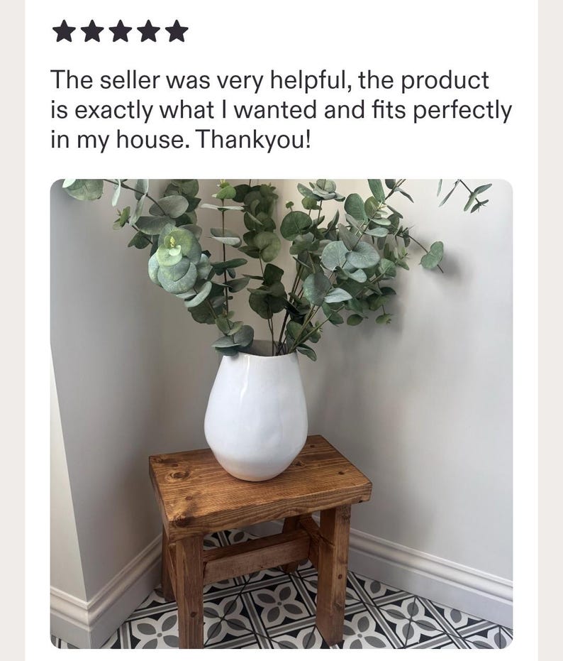 May include: A white ceramic vase with a smooth, rounded body containing green eucalyptus branches, placed on a small, rectangular, dark-stained wooden stool with four legs. The text above reads: The seller was very helpful, the product is exactly what I wanted and fits perfectly in my house. Thankyou!