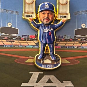 Könnte beinhalten: Anstecknadel mit einer Wackelkopf-Figur von Ice Cube im Dodgers-Trikot, der zwei World Series-Trophäen hält. Die Trophäen sind mit 2024 und 2025 beschriftet. Die Anstecknadel befindet sich vor einem Baseballfeld-Hintergrund mit dem Text "CM PINS".