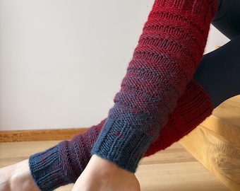 May include: Red and blue knitted leg warmers. The leg warmers have a ribbed cuff in a dark blue color, transitioning to a red and blue herringbone pattern. The leg warmers are designed to be worn on the lower legs.