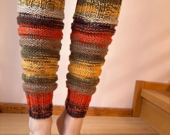 May include: A pair of hand-knitted leg warmers in a mix of autumnal colors. The leg warmers feature bands of brown, orange, yellow, and green. The ribbed cuffs and textured knit create a cozy, warm look. These leg warmers are perfect for cold weather.
