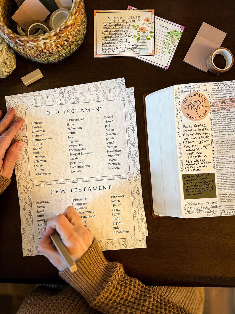 May include: A Bible study setup with a printed list of Old and New Testament books, a Bible, and decorative stationery. The image includes a handwritten memory verse and the words "ROOTED IN GOD'S TRUTH STAND FIRM."