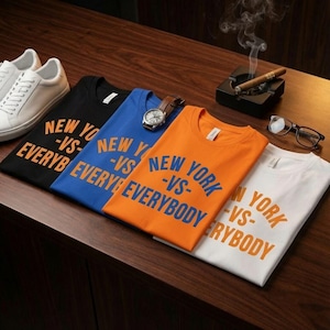 May include: Four t-shirts in black, blue, orange, and white, each featuring the text NEW YORK -VS- EVERYBODY. The collection includes a pair of white sneakers, a wristwatch with a brown leather strap, a pair of eyeglasses, and a cigar in an ashtray.