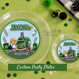 Op de afbeelding: Transparante plastic feestbordjes met een groen en blauw grafisch ontwerp met een cartoon vuilniswagen, een jongen en de tekst "Jaxon's Trash Bash". De borden zijn versierd met groene en witte confetti.