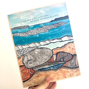 May include: Artwork of a beach scene with blue water, sand, and rocks. The artwork includes the text "...I just want to sit on the beach... ...and forget everything for a while..." The artwork is on a wooden panel.