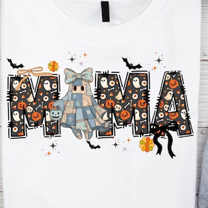 May include: White t-shirt with the word "MAMA" in a Halloween-themed design. The letters are filled with pumpkins, ghosts, and candy corn. A patchwork ghost with a bow and a jack-o'-lantern is in the center. Bats and stars are scattered around the letters.