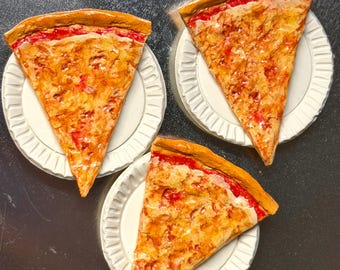 May include: Three slices of pizza on white paper plates. The pizza has a golden-brown crust, red sauce, and melted cheese. The plates are arranged on a silver surface, creating a visually appealing food-themed composition.