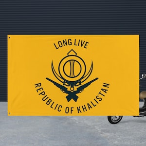 Könnte beinhalten: Ein gelbes Banner mit schwarzem Text und Grafiken. Der Text lautet "LONG LIVE REPUBLIC OF KHALISTAN". Die Grafik enthält ein kreisförmiges Emblem mit gekreuzten Gewehren. Das Banner wird im Freien gezeigt.