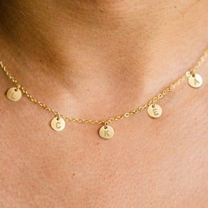 May include: A gold chain necklace with five small gold circles hanging from it. Each circle has a letter engraved on it, spelling out the word 'LUCKY'.