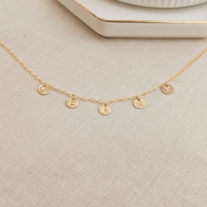 May include: A gold chain necklace with five small gold discs, each with a letter engraved on it. The letters spell out "GRACE".
