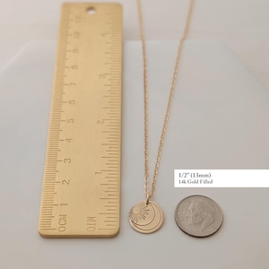 May include: A gold-colored necklace with a pendant featuring a sun and moon design. The pendant is approximately 1/2 inch (13mm) in diameter. The text "14k Gold Filled" is also visible.