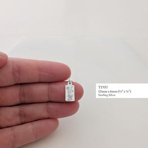 May include: A small, rectangular sterling silver pendant, 12mm x 6mm (&frac12;" x &frac14;"), featuring a delicate floral design. The word "TINY!" is printed on the image.