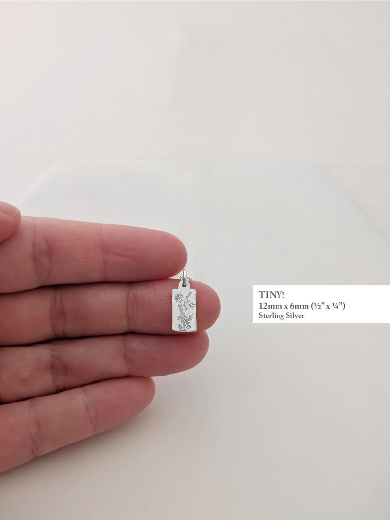 May include: A small, rectangular sterling silver pendant, 12mm x 6mm (&frac12;" x &frac14;"), featuring a delicate floral design. The word "TINY!" is printed on the image.