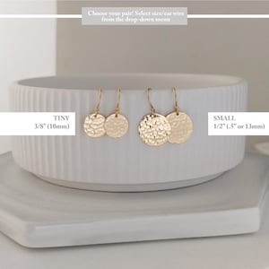 May include: Gold-colored disc earrings in two sizes: tiny (3/8 inch) and small (1/2 inch). The earrings are displayed on a white, textured bowl. The text on the image reads: "Choose your pair! Select size/ear wire from the drop-down menu."