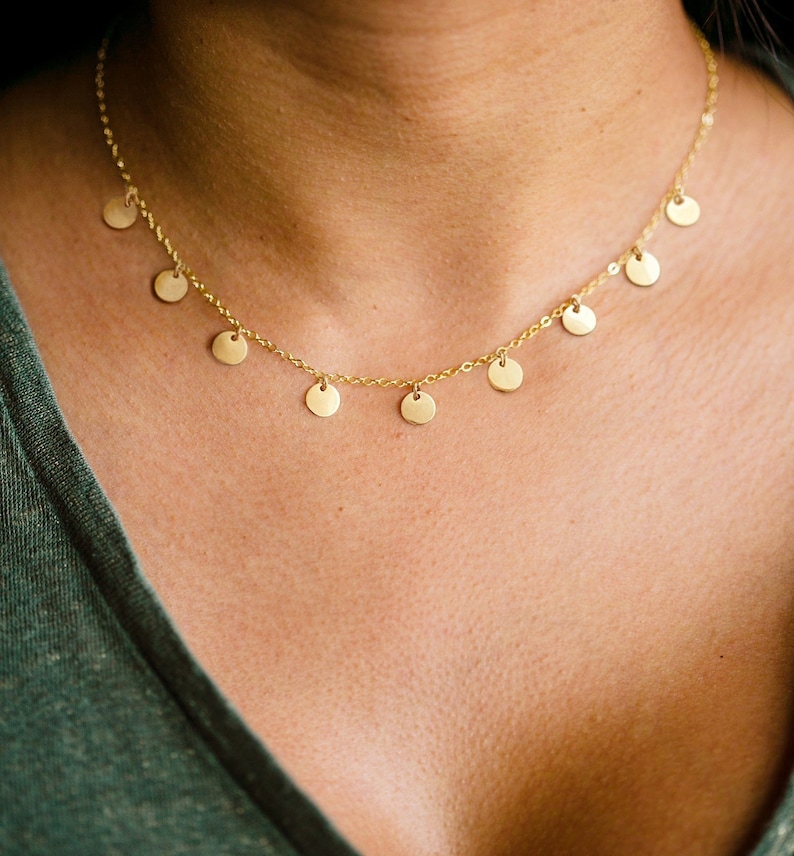May include: A gold necklace with a delicate chain and multiple small, round pendants.