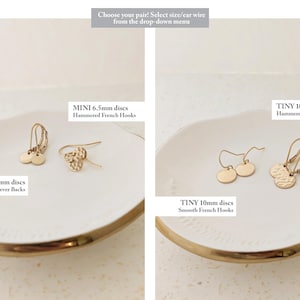 May include: Gold-colored disc earrings in two sizes, MINI 6.5mm and TINY 10mm, displayed on a white plate with a gold rim. The earrings feature smooth and hammered textures, with various hook styles. Text on the image reads "Choose your pair!"