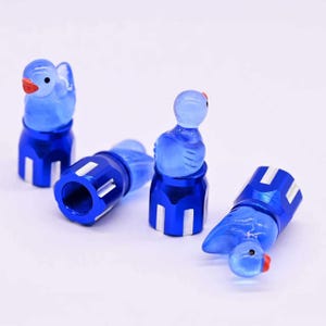 May include: Four blue bird-shaped valve stem caps with red beaks and white accents. The caps are made of metal and plastic. The caps are designed to fit on the valve stems of a car's tires. The caps are a decorative accessory.