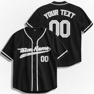 Könnte beinhalten: Schwarzes Baseballtrikot mit weißen Abschlüssen und einem weißen Teamnamen und einer weißen Nummer auf der Vorderseite. Die Rückseite des Trikots hat einen weißen Text mit der Aufschrift "YOUR TEXT" und eine weiße Nummer.
