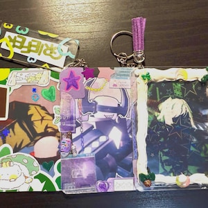 May include: A selection of decorative keyrings and card holders. The keyrings include a purple tassel and a clear rectangular tag with the word "GRIFFER". The card holders feature diverse, colourful designs, including stickers and illustrations.