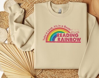 May include: A beige sweatshirt with a rainbow and the text "Take a Look, it's in a Book! Reading Rainbow" printed on the front.