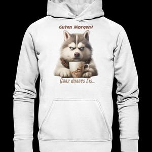 Könnte beinhalten: Ein weißer Kapuzenpullover mit einer Grafik eines grau-weißen Huskys mit mürrischem Gesichtsausdruck, der eine Kaffeetasse hält. Der Text über dem Hund lautet "Guten Morgen?" und der Text unter dem Hund lautet "Ganz dünnes Eis..." in Braun.