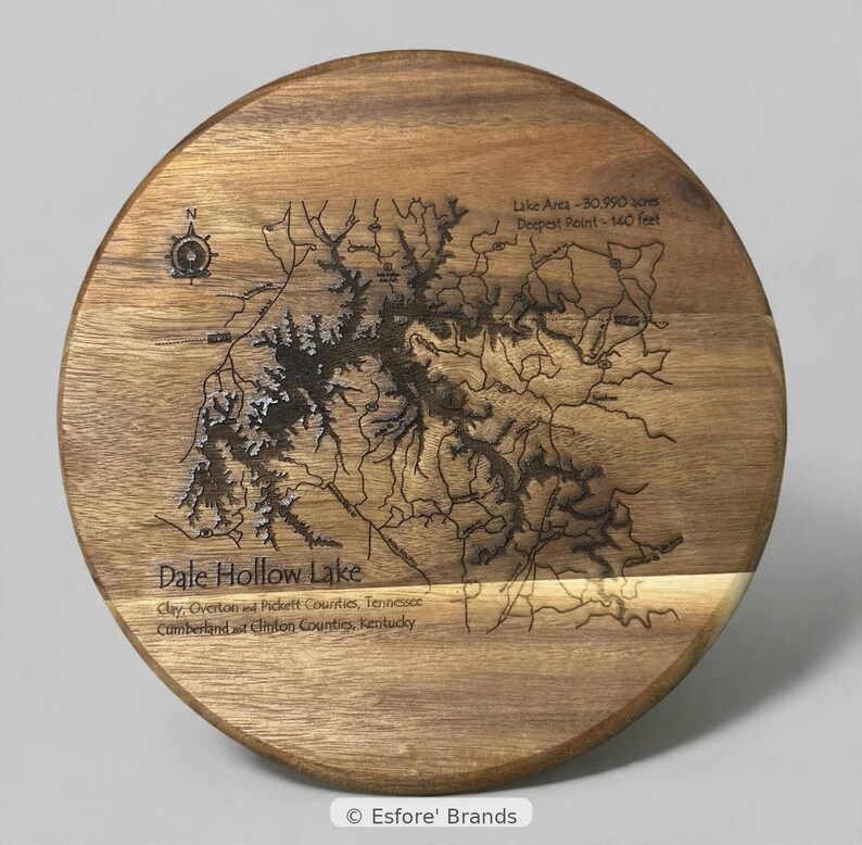 Puede incluir: Una tabla de servir redonda de madera con un mapa grabado con l&aacute;ser del lago Dale Hollow. El dise&ntilde;o incluye una rosa de los vientos, estad&iacute;sticas de &aacute;rea y profundidad del lago, y los nombres de los condados circundantes.
