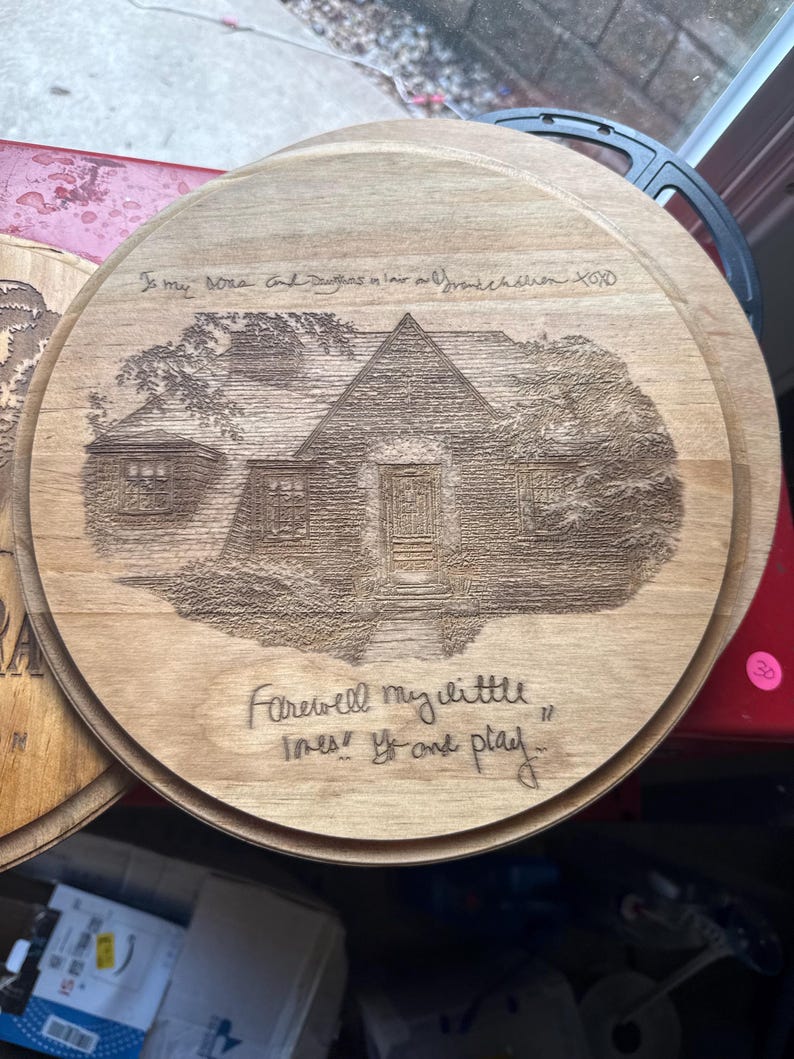 May include: A round wooden plaque featuring a laser-engraved illustration of a house. The text at the top reads "To my sons and daughters in law and grandchildren XOXO" and the bottom text reads "Farewell my little ones! Go and play."