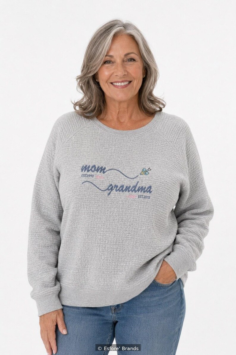 May include: A light gray long-sleeve sweatshirt with a textured waffle-knit fabric. The front features the text "mom EST.1992" and "grandma EST.2012" in dark blue script, accented by a small colorful butterfly graphic.