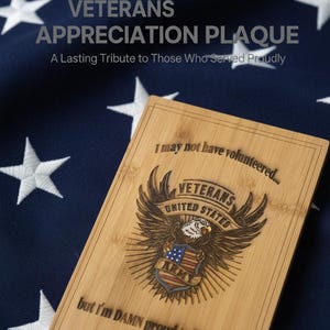 May include: A rectangular bamboo plaque featuring an engraved eagle emblem with a shield, the text "I may not have volunteered..." at the top, and "but I'm DAMN proud to be a VET!" at the bottom, centered on a dark blue fabric with white stars.