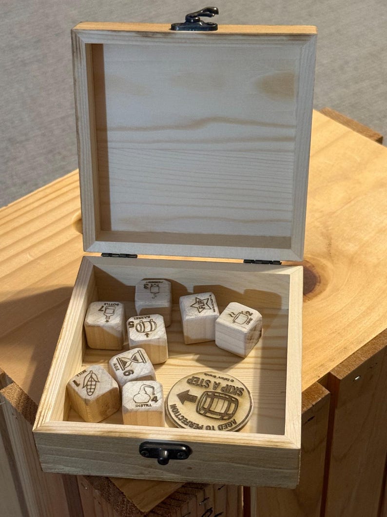 May include: A light-colored wooden box with a hinged lid and metal latch containing seven wooden dice and one circular wooden token. Each die features a unique icon and number. The token displays a barrel graphic and the text SKIP A STEP.
