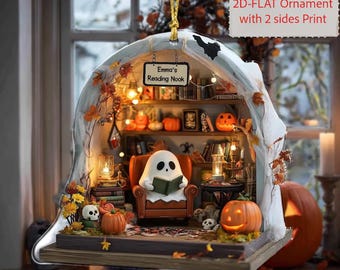 May include: A customized 2D-flat Halloween ornament with a ghost reading in a cozy nook. The ornament features a miniature library with pumpkins, skulls, and the text "Emma's Reading Nook". The ornament is suspended by a gold string.
