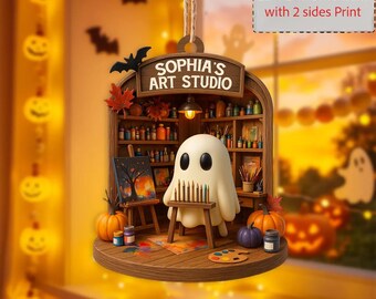 May include: A Halloween-themed ornament featuring a ghost artist in a studio setting. The ornament includes a miniature easel with a painting, pumpkins, and the text "SOPHIA'S ART STUDIO". The ornament is a 2D-flat design with printing on both sides.