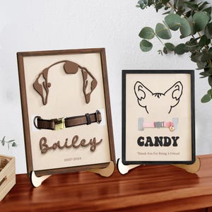 May include: Two wooden pet memorial frames with a dog and cat silhouette. The dog frame has a brown leather collar and the text "Bailey 2007-2024". The cat frame has a pink collar with a bell and the text "CANDY Thank You For Being A Friend".