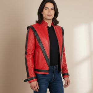 May include: A red leather jacket with black accents, featuring a stand-up collar and shoulder pads. The jacket has black stripes down the sleeves and a zipper closure. The model is wearing a black shirt and blue jeans.