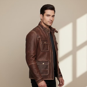 May include: A brown leather jacket with a classic design. The jacket features a stand-up collar, multiple front pockets, and a front zipper closure. The jacket is made of distressed leather and has a rugged, vintage look.