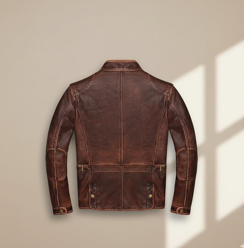 May include: A brown leather jacket with a distressed finish. The jacket features a classic collar, shoulder panels, and multiple pockets with button and buckle details. The back view showcases the tailored design and stitching.