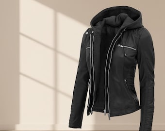 May include: A black jacket with a hood, featuring a zipper closure and multiple pockets. The jacket has a fitted silhouette with pleated detailing on the sleeves. The design includes silver zippers and a soft, matte finish.