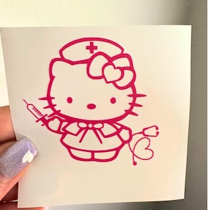 May include: A pink sticker featuring a cartoon character dressed as a nurse. The character wears a nurse's cap with a cross and holds a syringe and stethoscope. The design includes a bow and heart details.